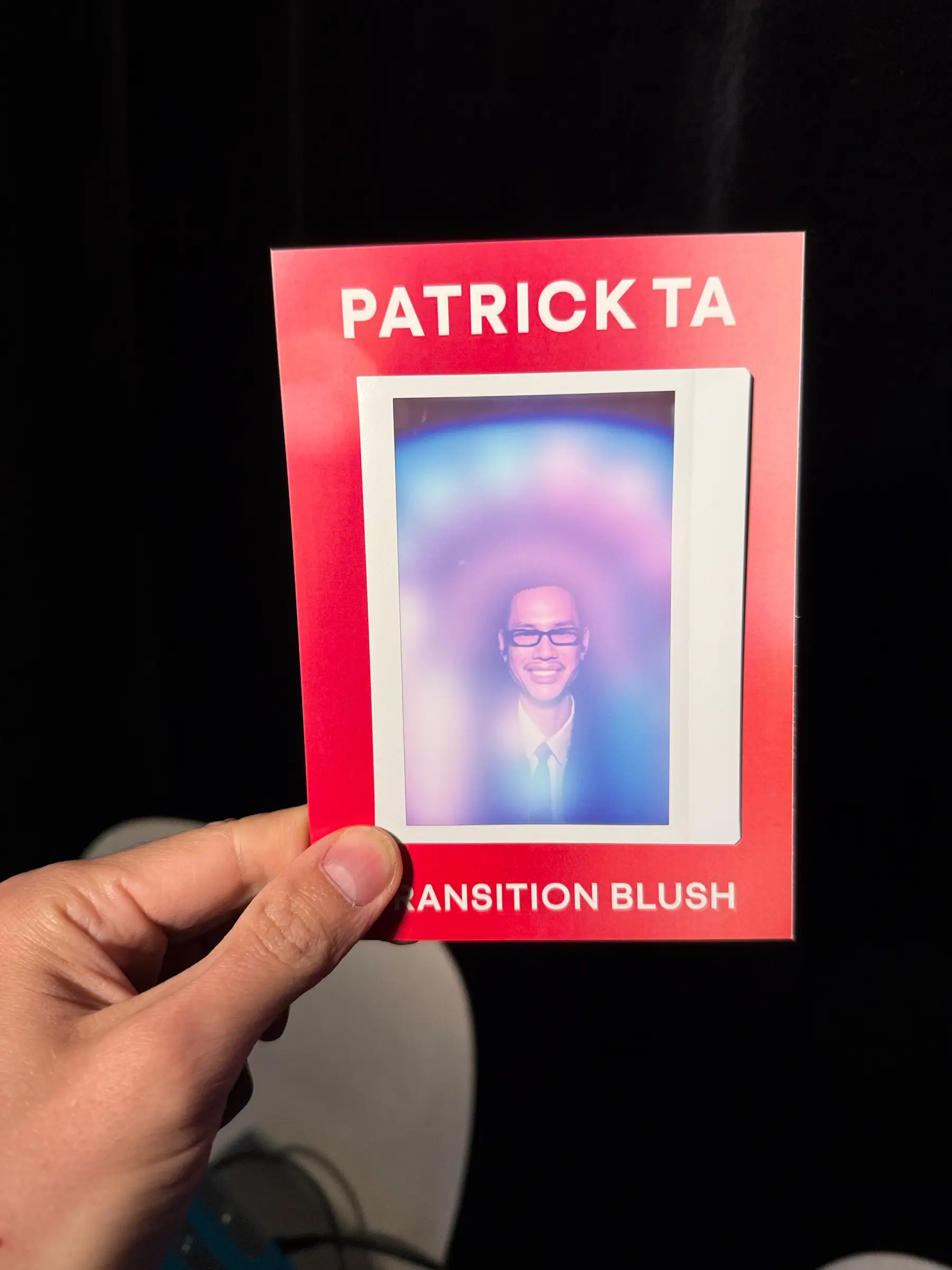 Hand holding a branded Patrick Ta aura photography keepsake print